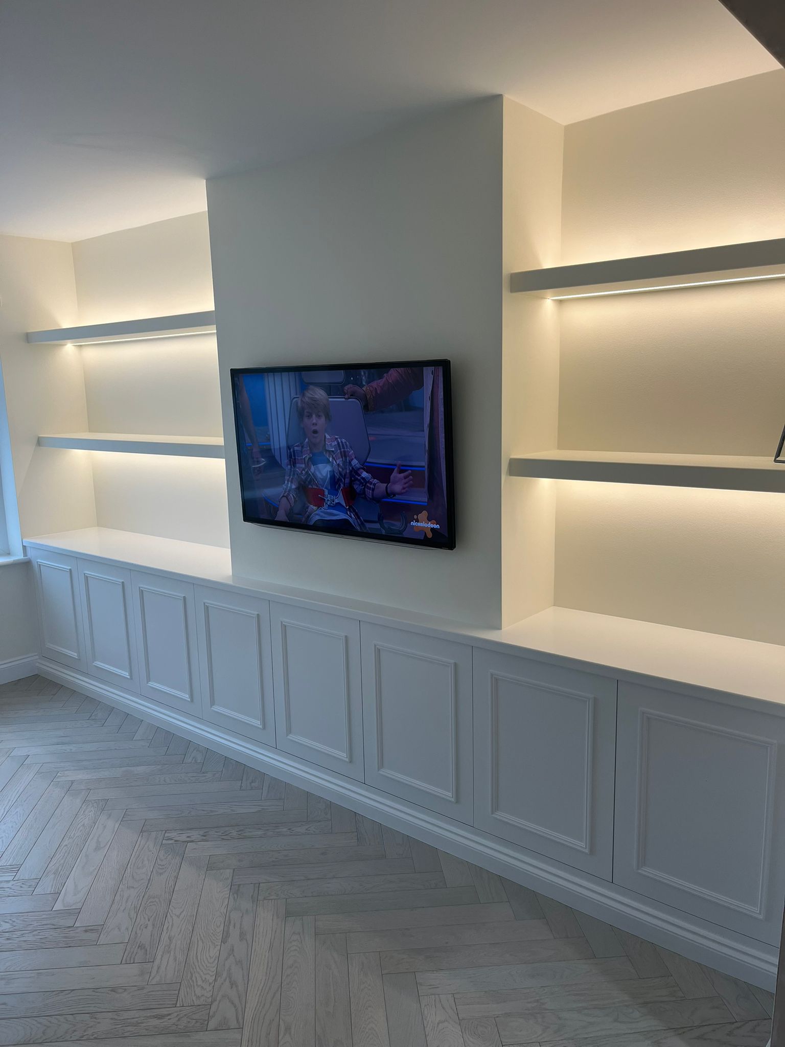 After: bespoke media wall with LED shelving, built-in cabinets and herringbone flooring
